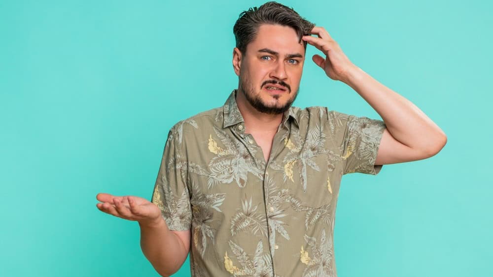 Middle-aged man shrugs shoulders, raises palms with puzzled facial expression, clearly indicating lack of knowledge or uncertainty. Young adult guy isolated on blue background showing honest confusion
