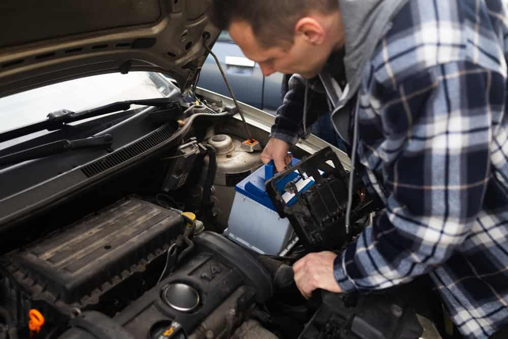 The man removed the car battery from the car in order to have it repaired or replaced. Transport service.
