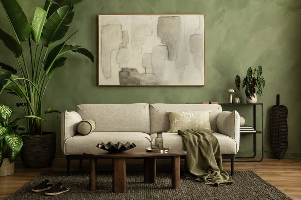 Modern interior with soft neutral sofa, organic shapes, textured rug, and warm green wall backdrop.