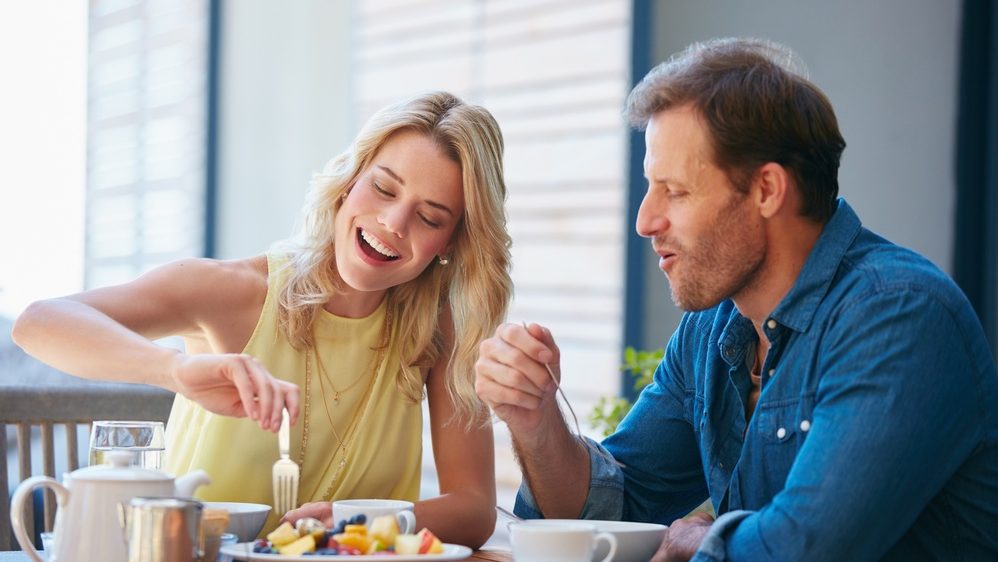 House, eating and couple with breakfast, love and bonding together with healthy meal. Apartment, man and woman with food, nutrition and care with wellness, protein and calm with relationship or talk