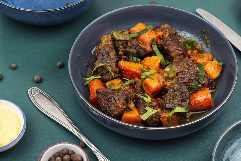 Tender beef stew with sweet potato pieces and fresh herbs in dark flavorful gravy.