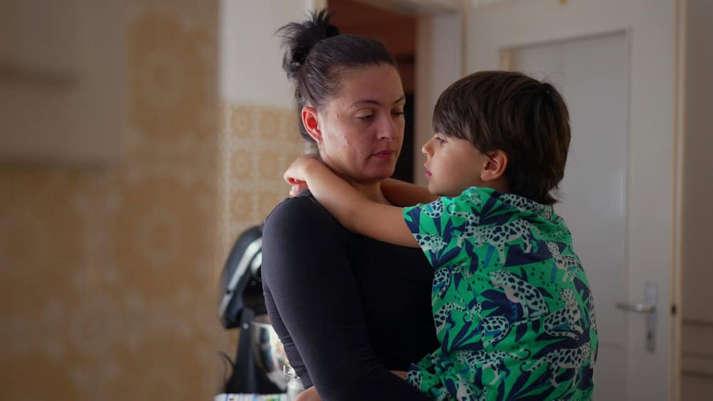 Mother holding child close, sharing a moment of connection and conversation in a cozy kitchen environment, emphasizing family bonding and love