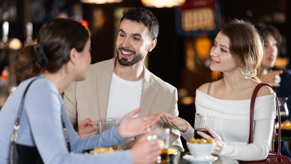 Young man meets women in a bar, they smile at each other and actively communicate and ask questions
