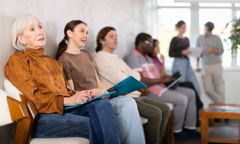Senior woman is waiting for her turn for an interview in the office, she came to apply for an open vacancy. Candidates sit in the waiting area before the interview.