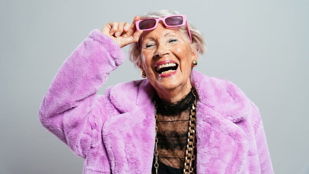 image of a beautiful and elegant old influencer woman. Cool grandmother posing in studio wearing fashionable clothes. Happy senior lady celebrating and making party. Concept about seniority and lifestyle