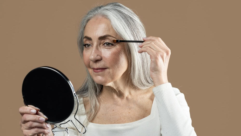 Senior Woman Applying Makeup In Front Of Mirror, Skincare Concept