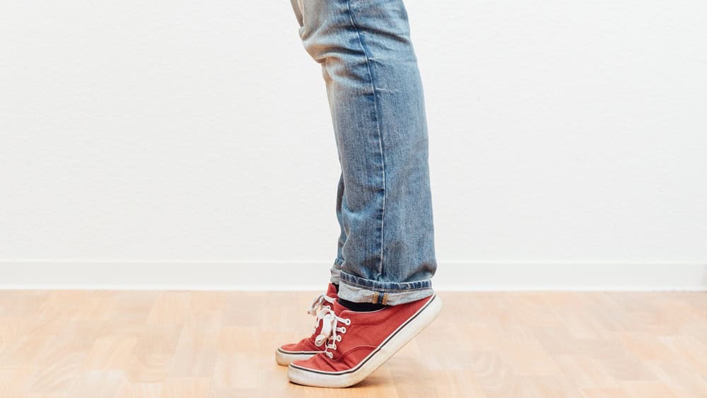 Man on tip toes, anonymous bottom half crop, indoors studio people shot.