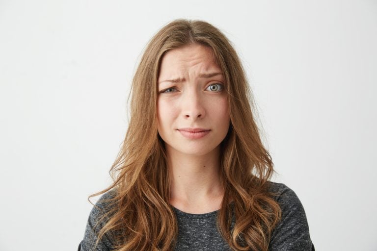 Portrait of young pretty girl looking at camera with contempt over white background.