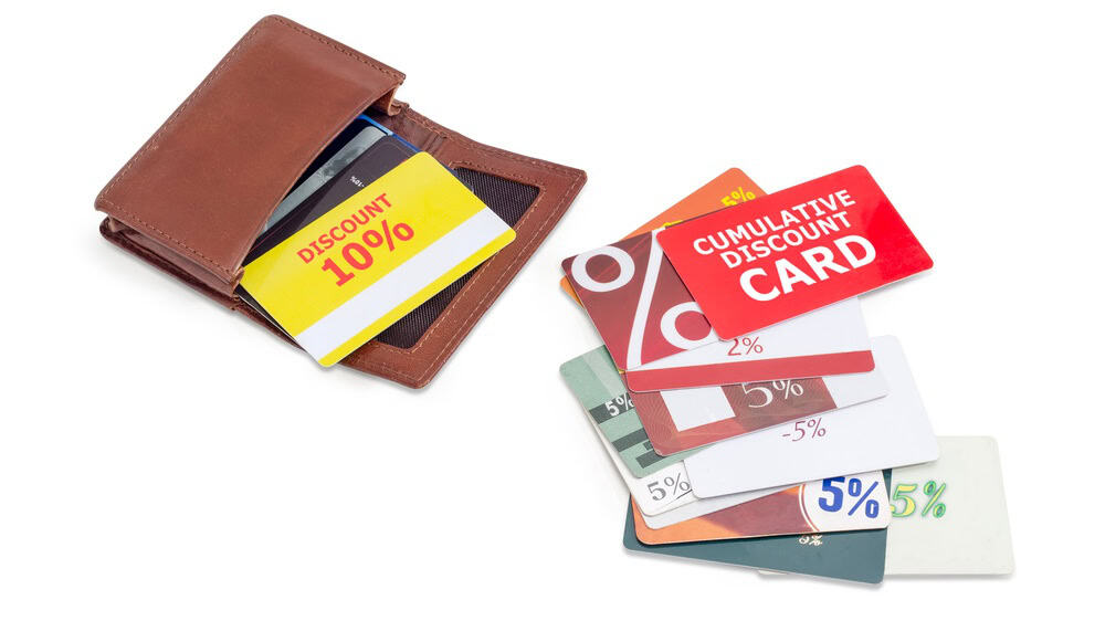 Different discount cards in open special brown leather wallet and beside to him closeup on a white background