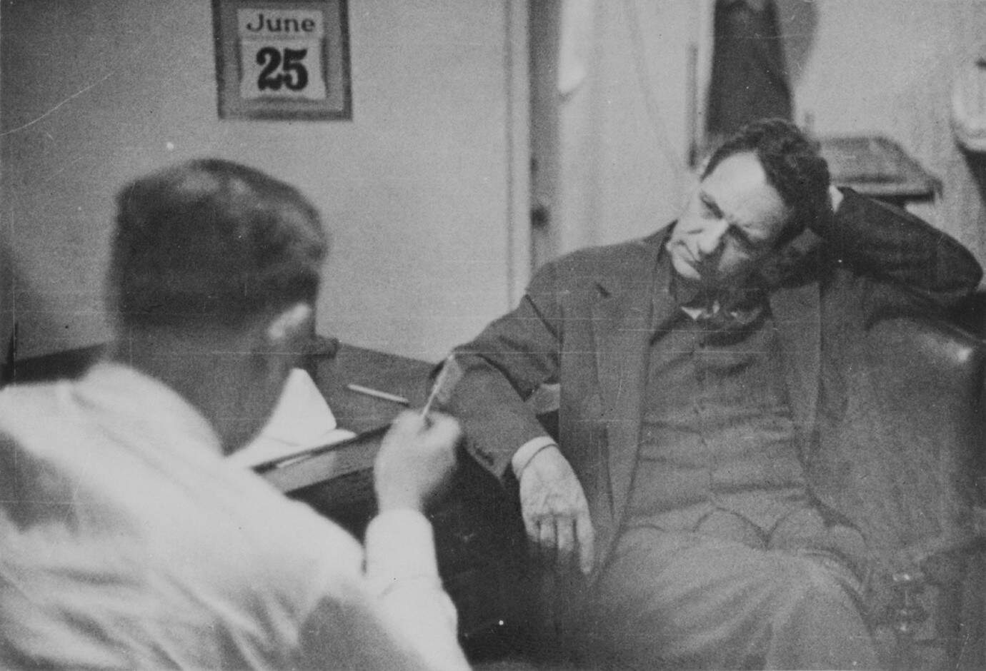 FBI agent talks with Captain Fritz Joubert Duquesne, German spy, who was unaware that FBI agents were taping the whole episode behind a two-way mirror.