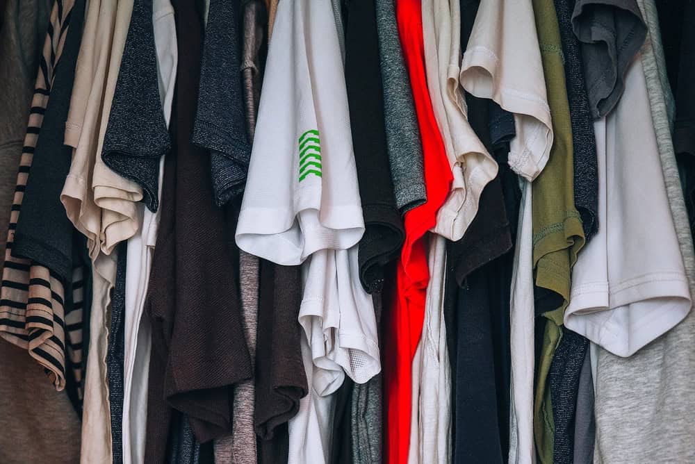 Many colorful clothes hanging on hanger. Charity donation, thrift store, garage sale or full closet at home.