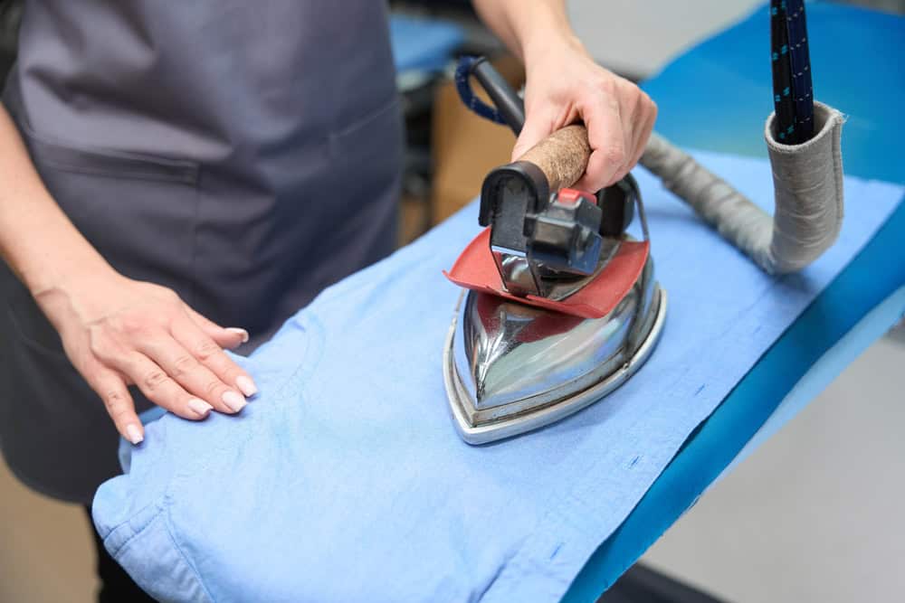 Woman using a hot iron to remove wrinkles from a shirt