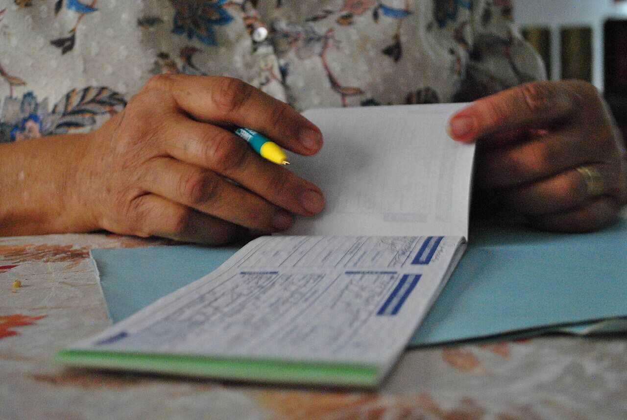 Close-up of an older woman's hands writing in a checkbook