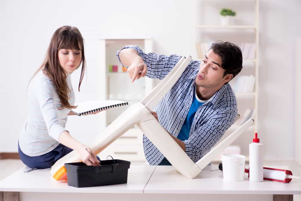 Wife helping husband to repair broken chair at home