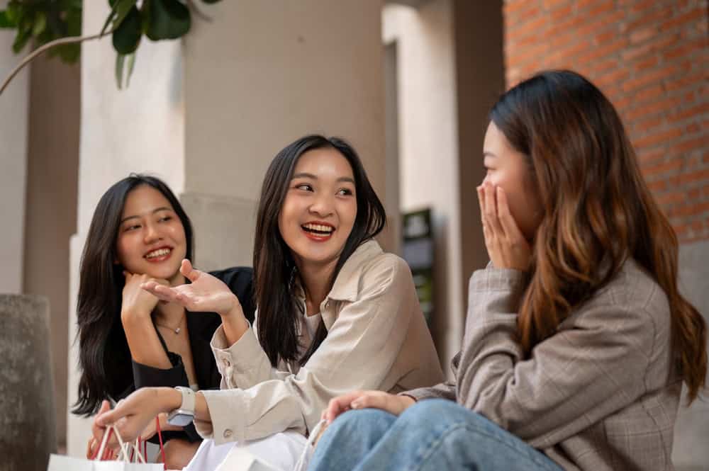 A beautiful young Asian female is enjoying talking with her friends while resting on the stairs afte