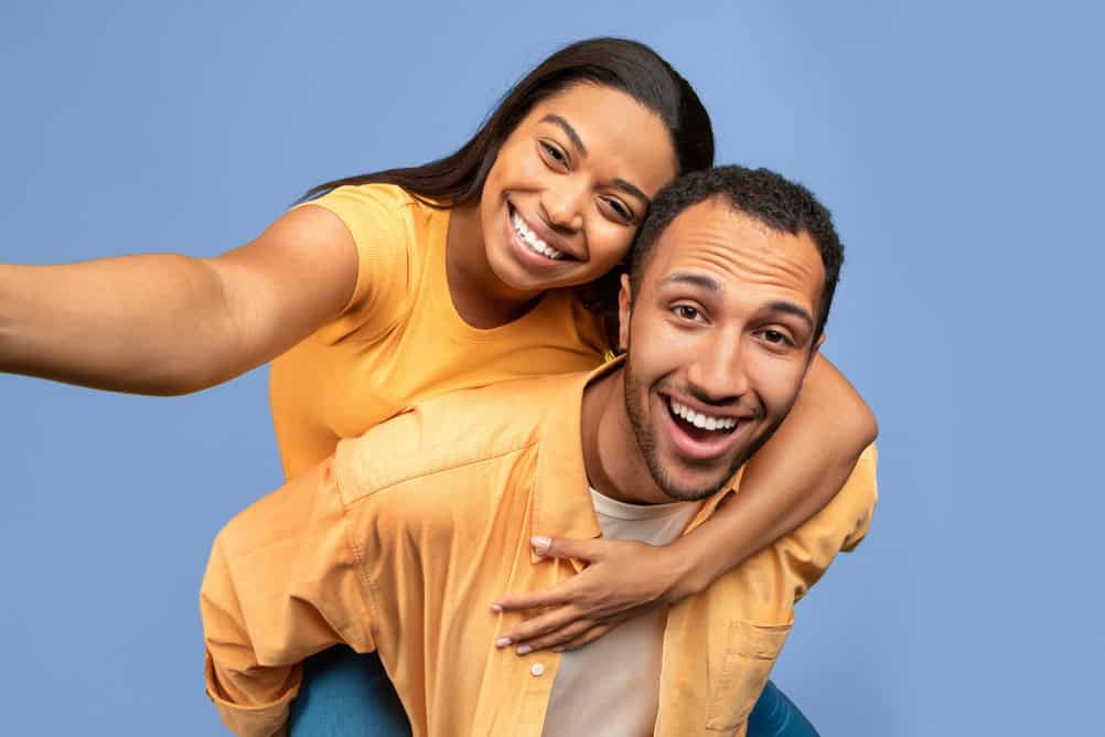 Happy Young Couple Smiling Together, Playful Pose, Blue Background