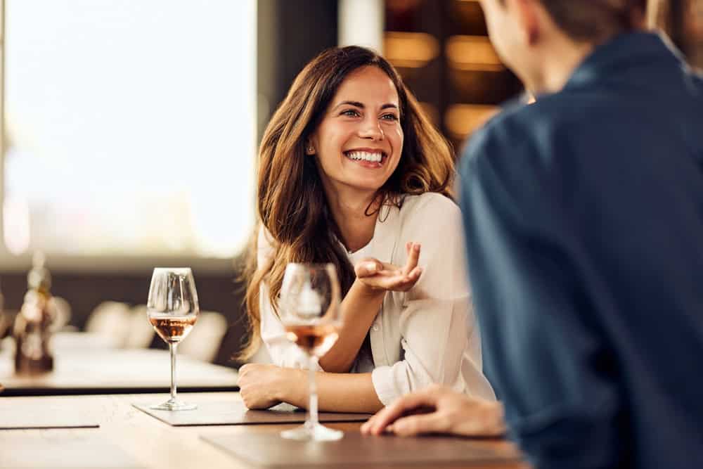 Happy woman engaging in lively conversation at a cozy social setting with wine.