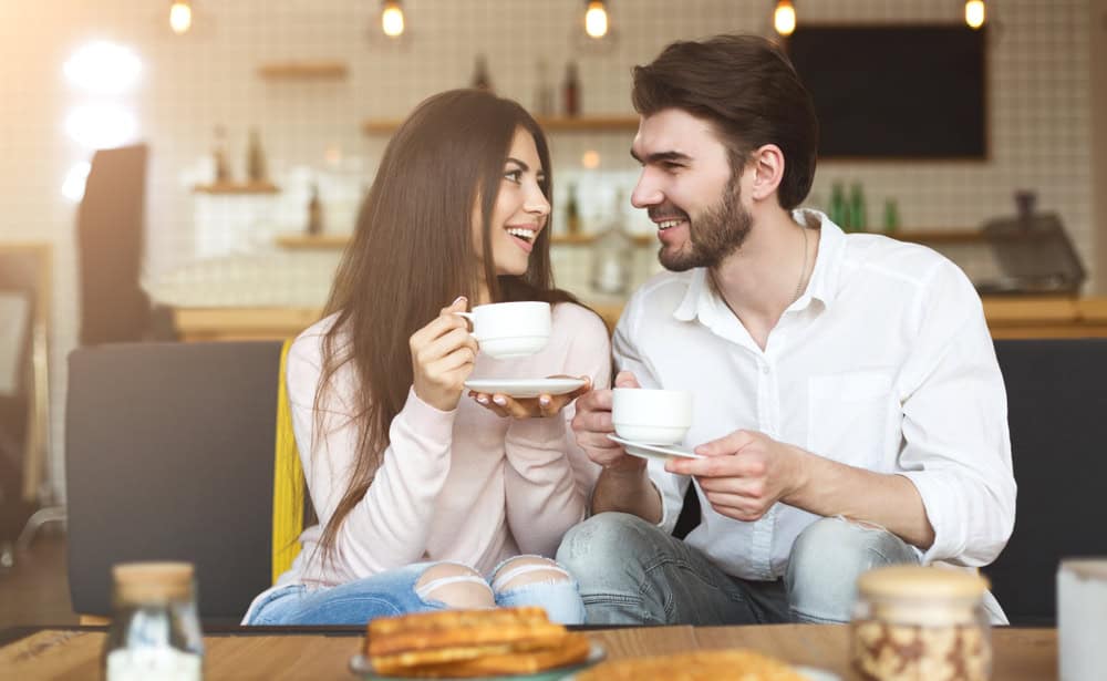 First date. Cute couple looking at each other in cafe and drinking morning coffee, copy space