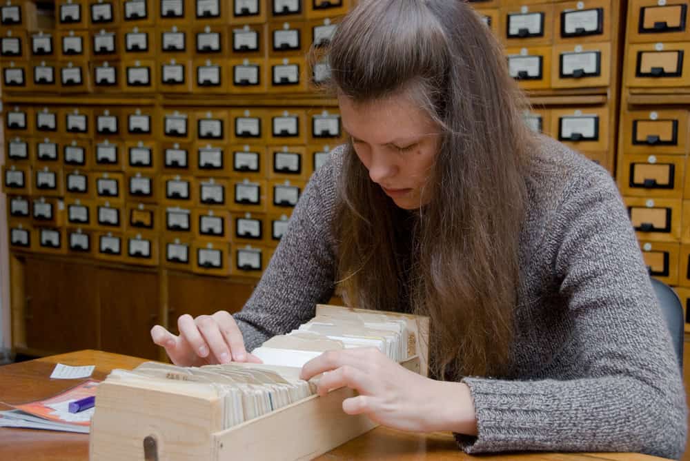 Young woman searching file in the library card index