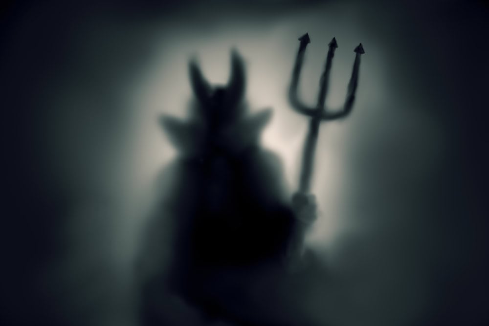 Creepy Devil silhouette behind a frozen glass and in the mist with backlit.