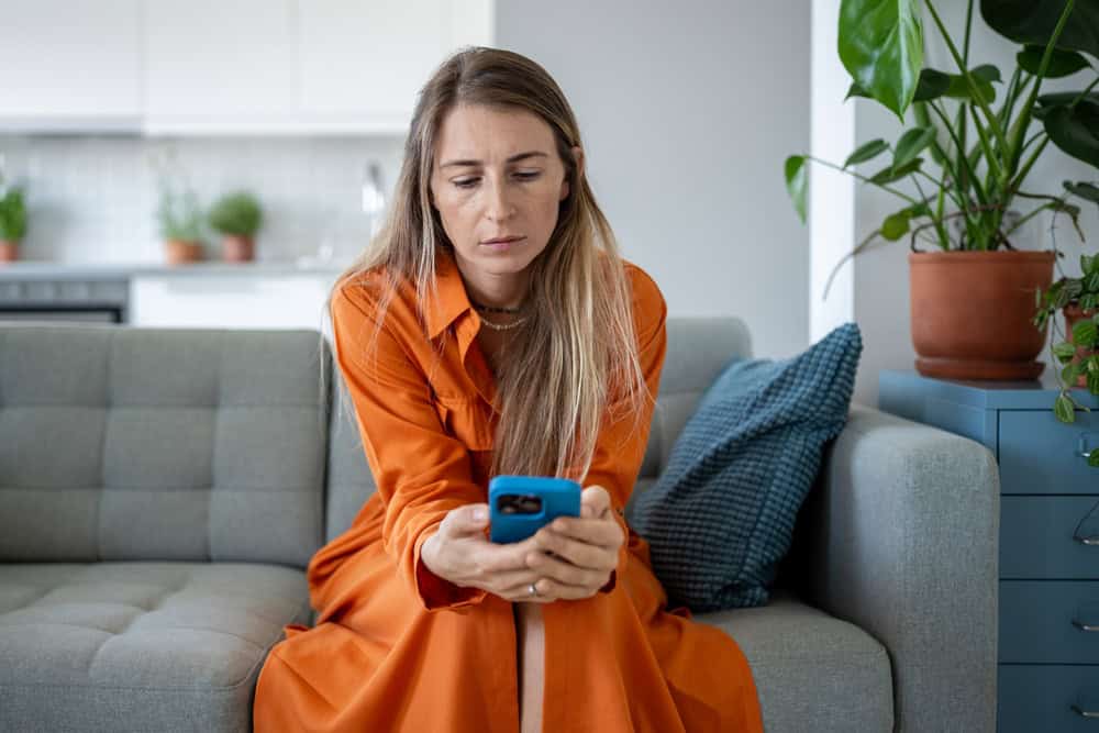 Sad woman holding mobile phone in hands, waiting for call or message. Frustrated female reading news, looking with strained uncertainty at smartphone with bad thoughts in head, loss of connection.