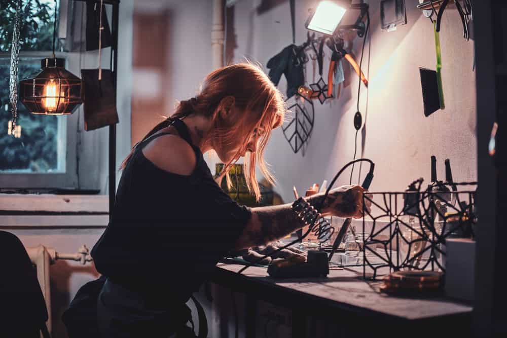 Talanted young woman is working on her own project at glass workshop.