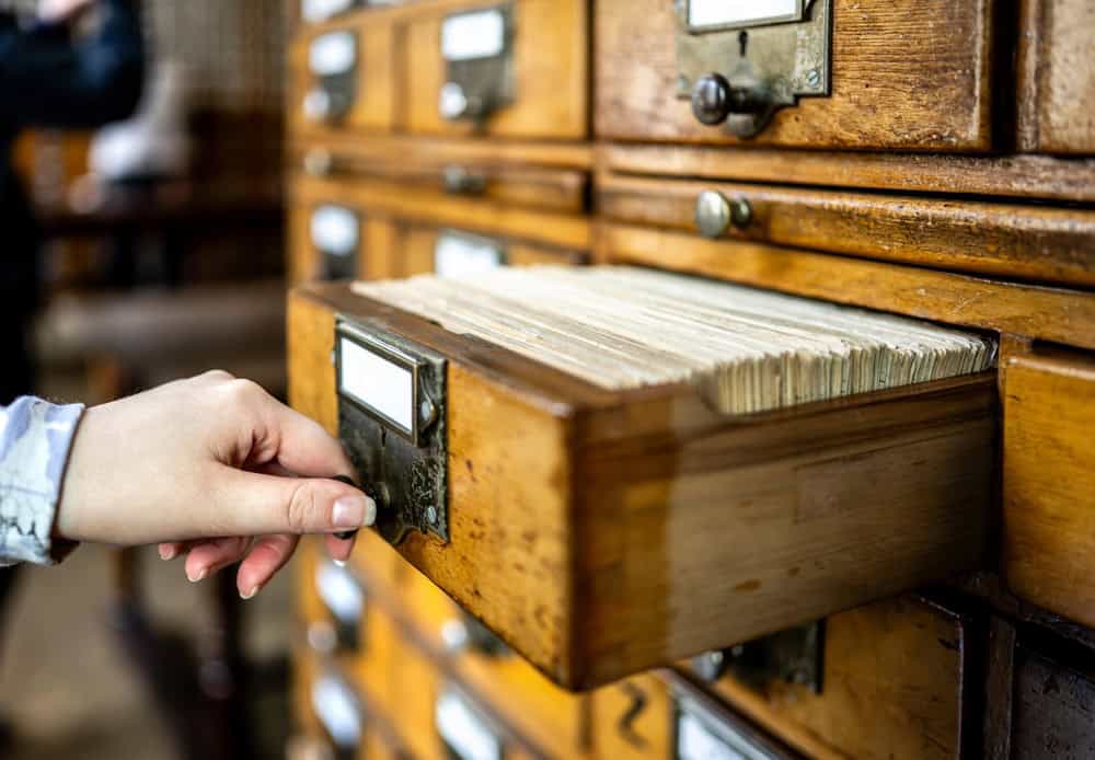 Woman's hand opening a library card catalog drawer