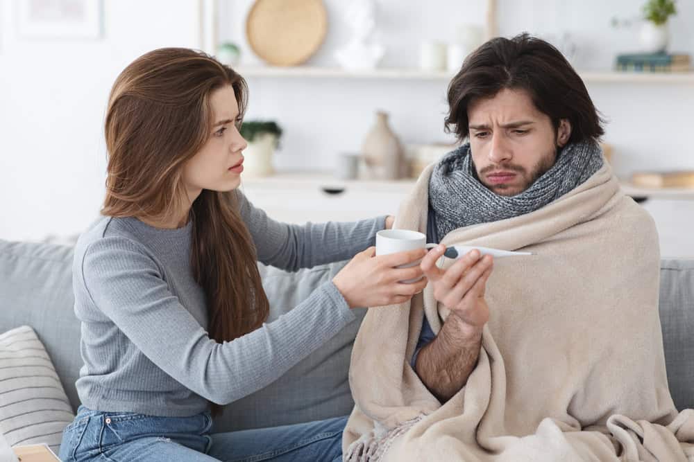 Attentive woman giving her sick boyfriend treatment, home interior