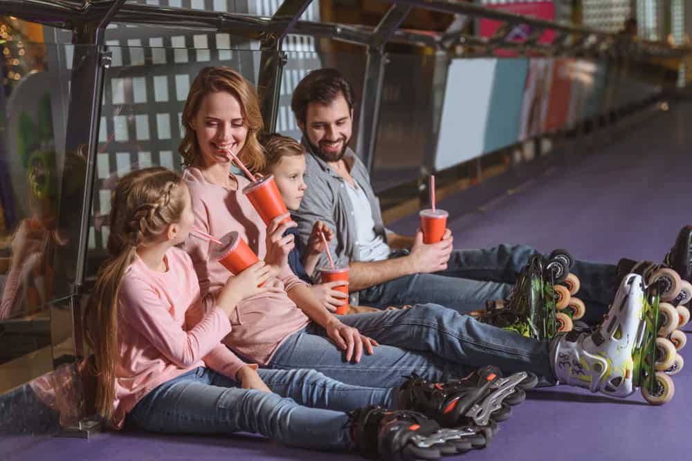 family with drinks resting after skating on roller rink