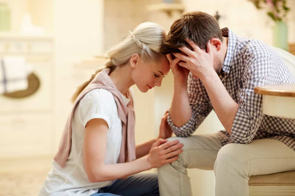 Young woman supporting her worried husband having troubles at work