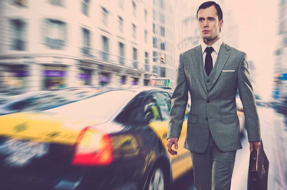 Man in classic grey suit with briefcase walking outdoors
