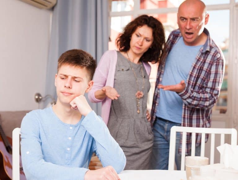 Portrait of troubled teenage boy and his parents scolding him