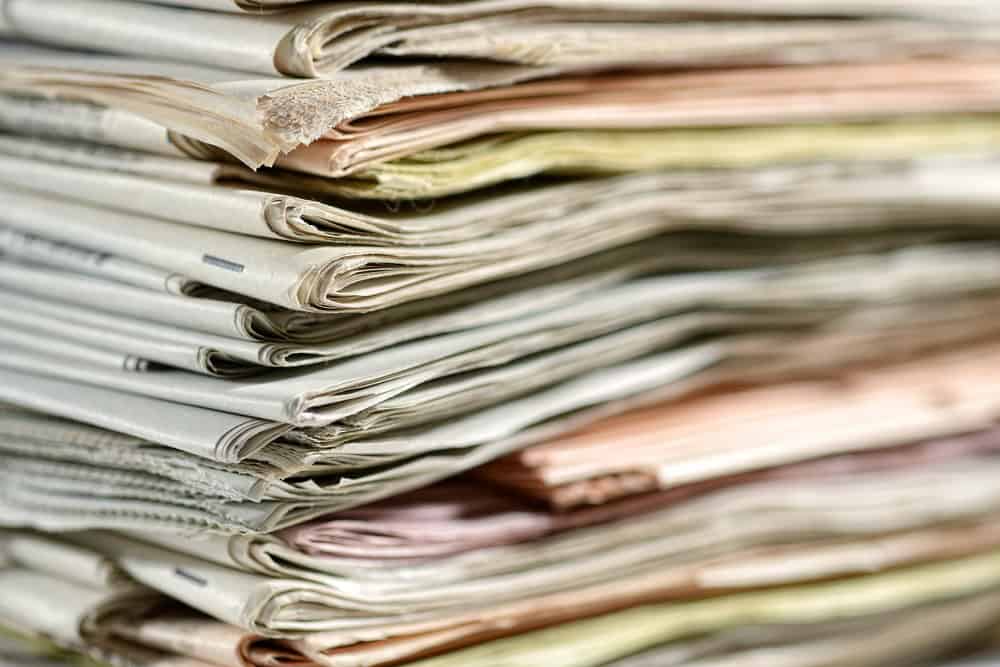 Neat stack of old newspapers with close up detail of the corner of the pile