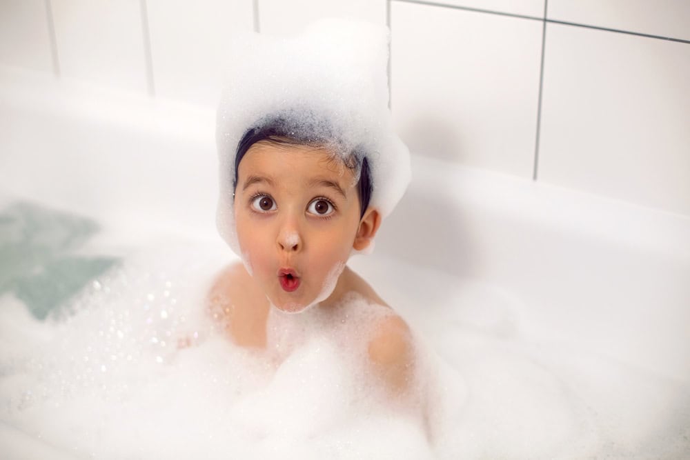 boy with big eyes a Caucasian child bathes in a white bath with foam