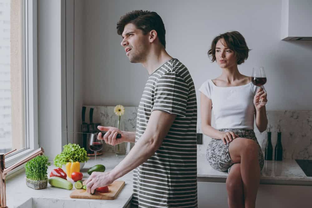 Young sad couple two woman man 20s wearing casual t-shirt clothes prepare vegetable salad girl sit on table drink red wine cook food in light kitchen at home together. Healthy diet lifestyle concept.