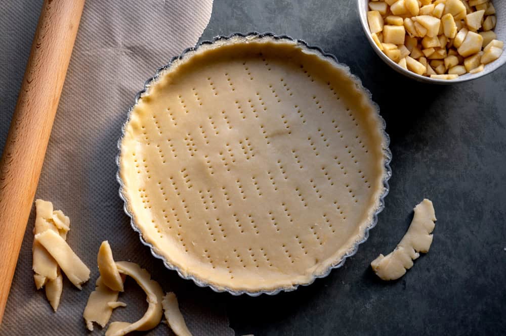 Homemade pie crust in pie plate. Cooking apple pie, dark background