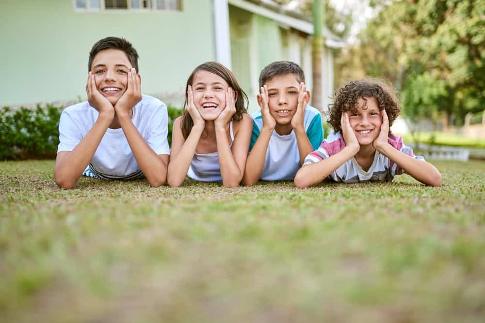 Siblings are best friends you cant live out. Portrait of a group of happy siblings lying together on the grass in their backyard.