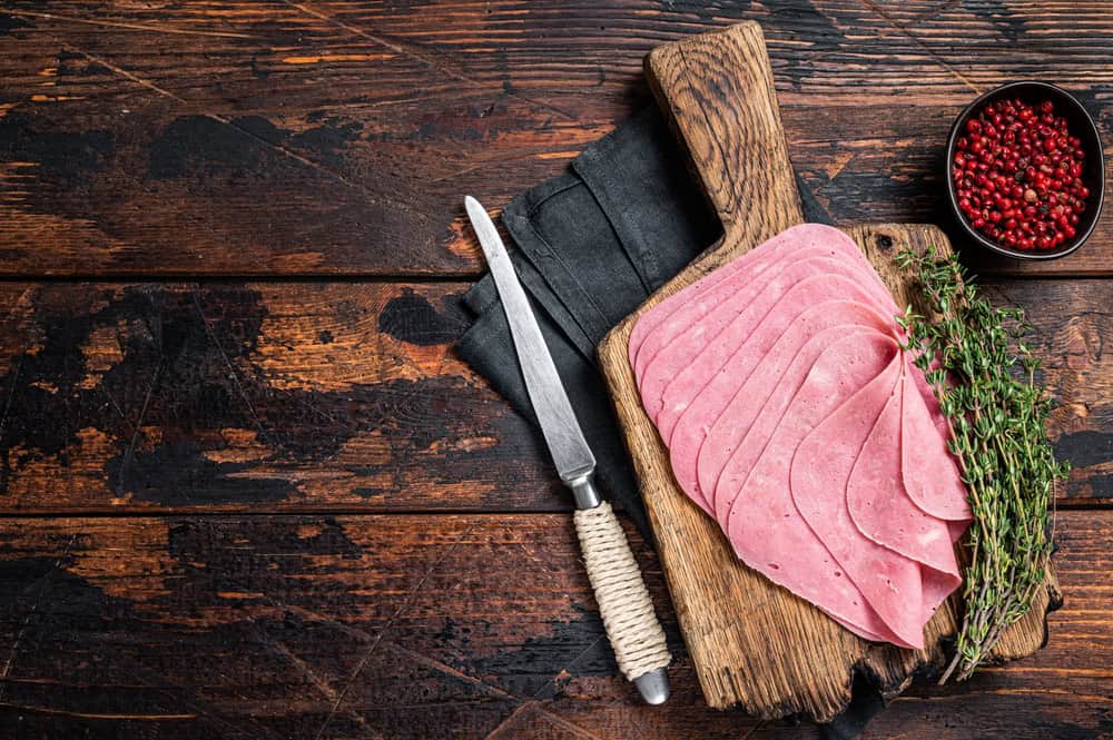 Sliced Beef Ham snack on wooden board. Wooden background. Top view. Copy space.