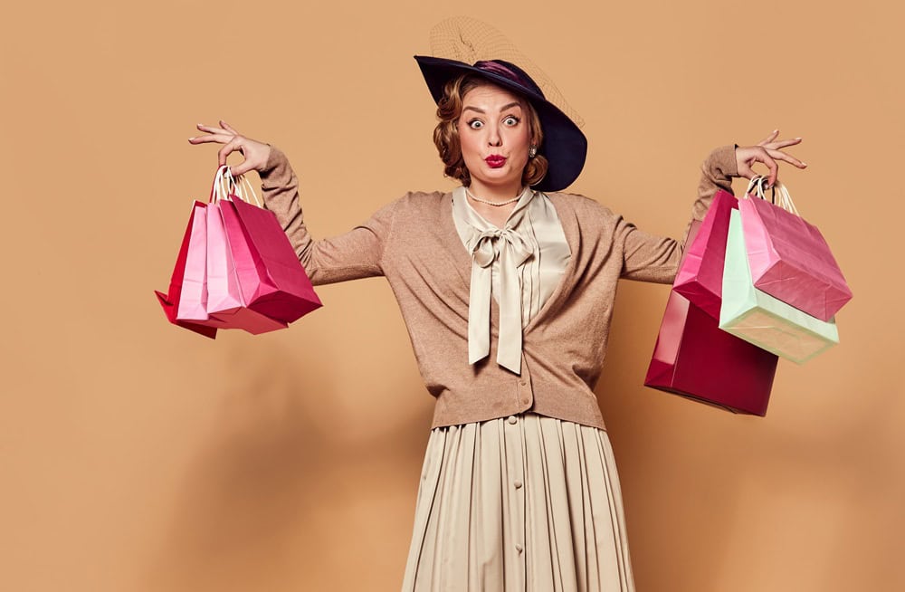 Shopping day. One charming woman wearing retro clothes holding paper bags over beige background. Concept human emotions, beauty, fashion, retro style, vintage, 60s. Sales, Black Friday