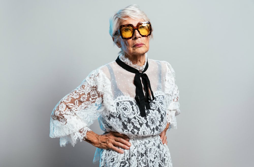 beautiful and elegant old influencer woman. Cool grandmother posing in studio wearing fashionable clothes. Happy senior lady celebrating and making party. Concept about seniority and lifestyle