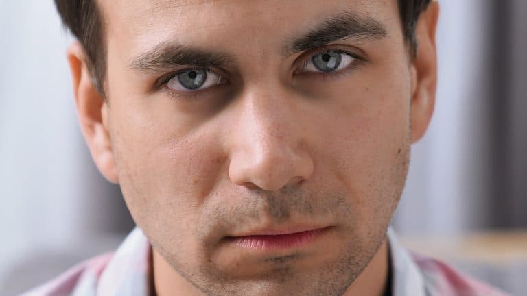 Brutal displeased 30s person look camera. Young adult guy head shot. Annoyed angry man portrait. One rude male face close up. Bad day mood. Scary tired mad gaze. Anger grim emotion. Black hair bristle