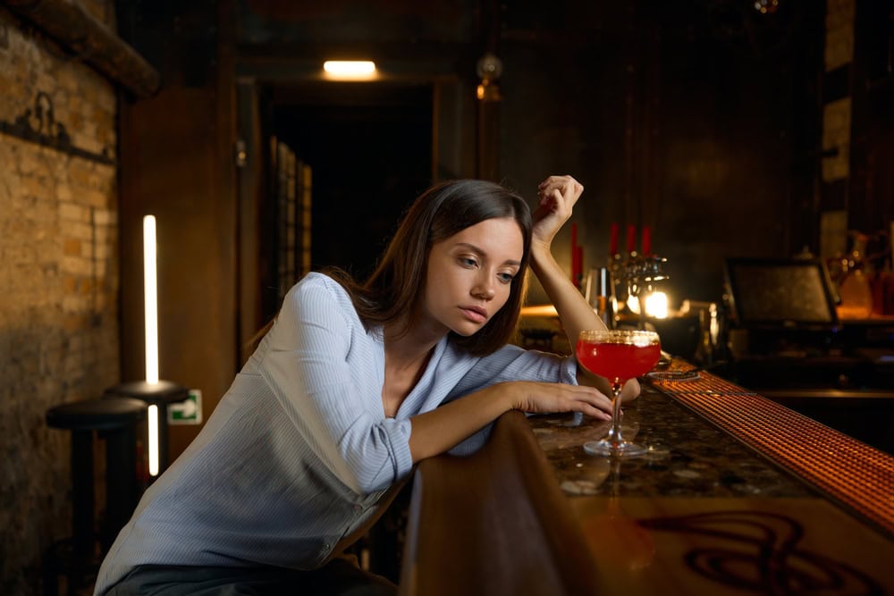 Lonely sad woman sitting at bar with glass of wine