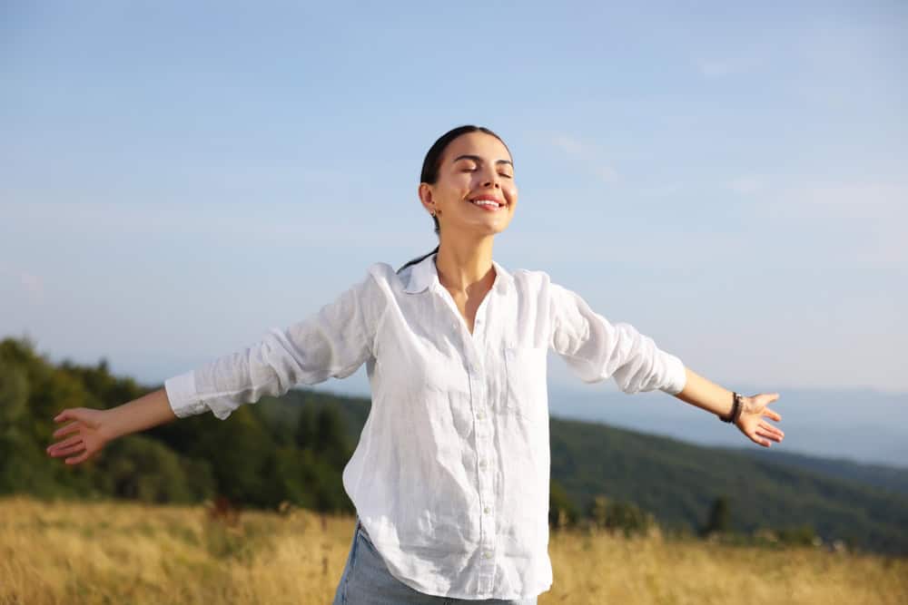 Feeling freedom. Happy woman with wide open arms outdoors