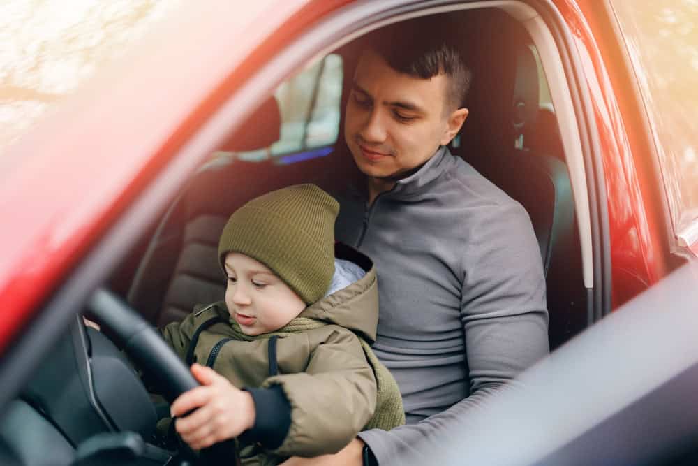 Man father teaches his little son to drive car. Concept love for cars since childhood.