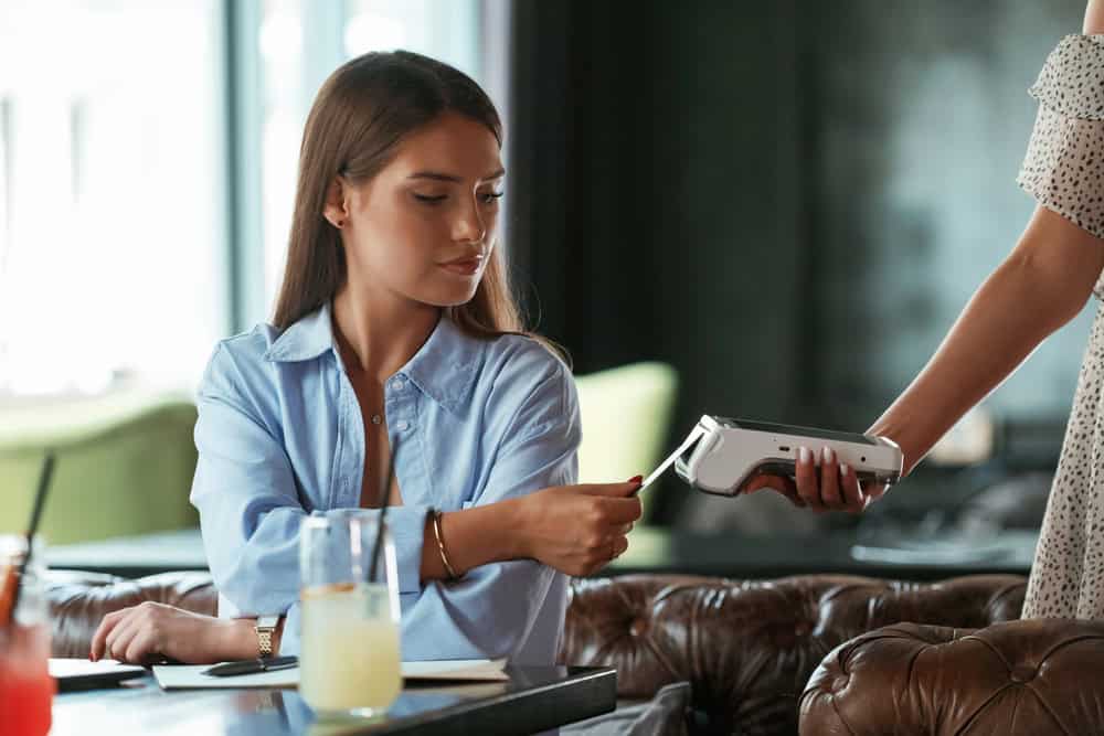 Using smartphone. Woman is paying for the service in the restaurant.