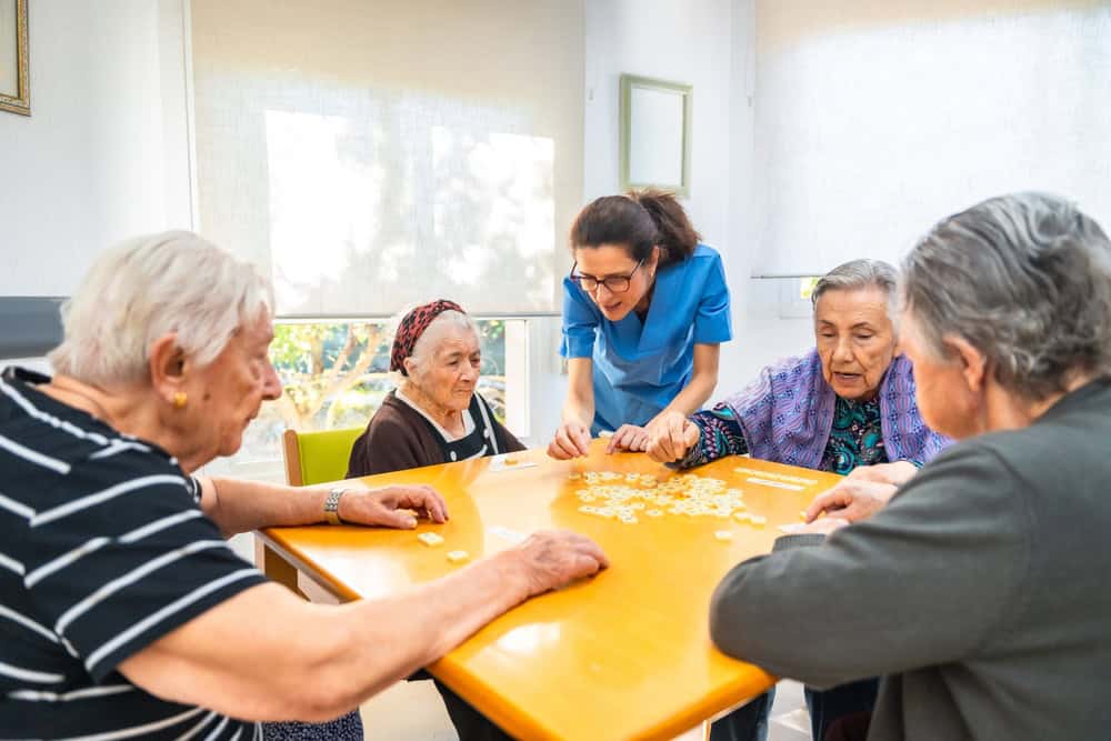 Female caucasian nurse and senior people playing board skill games in the nursing home