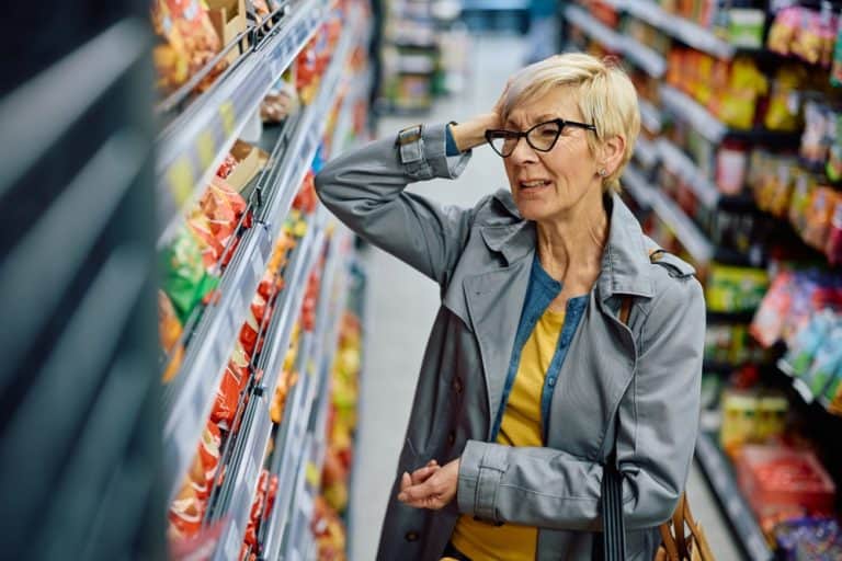 Senior woman feeling upset about grocery prices while shopping at supermarket. Copy space.