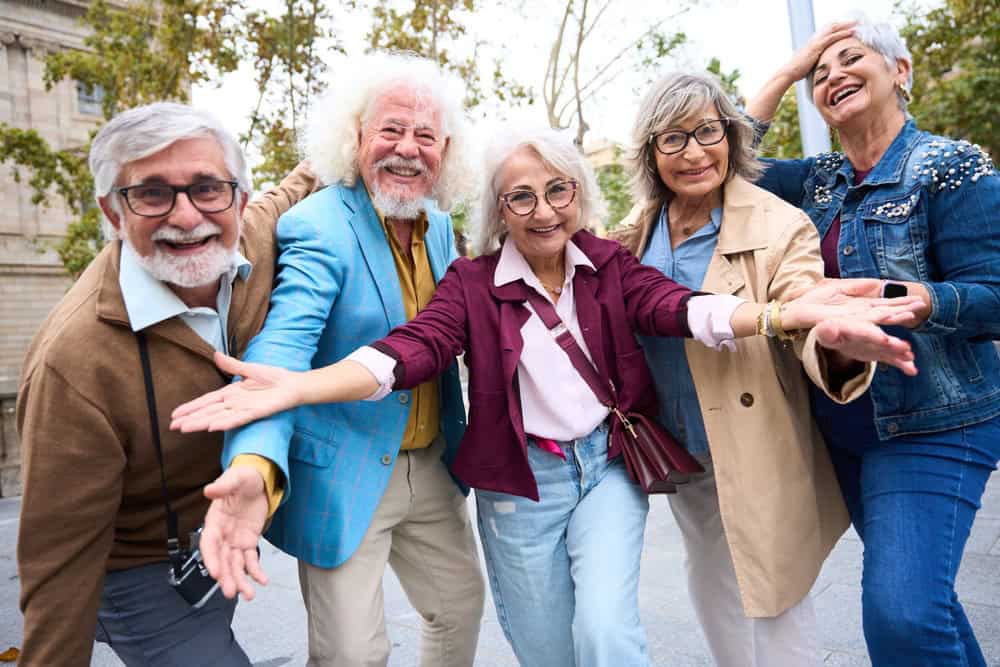 Fashionable senior friends laughing and exploring a sunny european city together, enjoying retirement travel and vibrant urban life