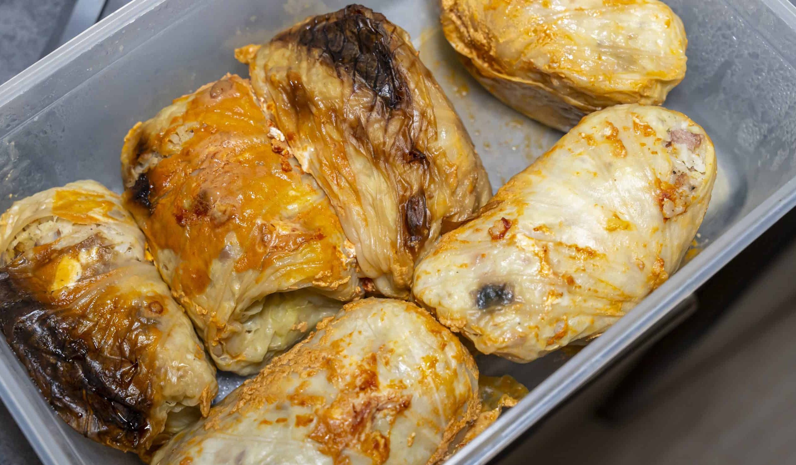 Baked cabbage rolls arranged in a container, exhibiting a golden-brown finish. Perfect for culinary photography, food blogs, and cooking-related content showcasing traditional cuisine.