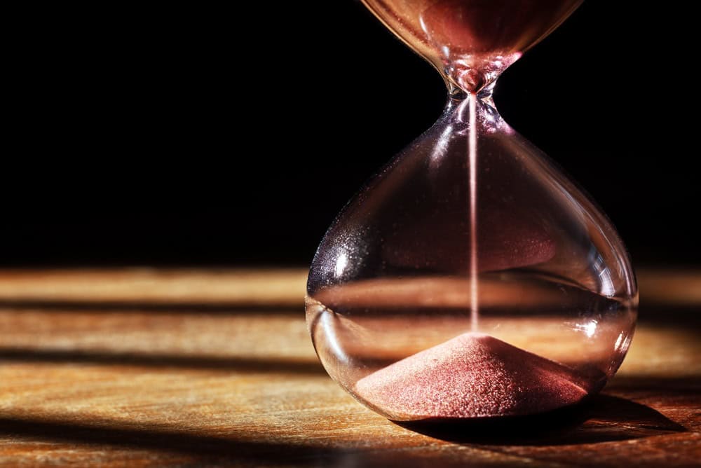 Hourglass time passing dark background with copy space concept for business deadline, urgency and running out of time